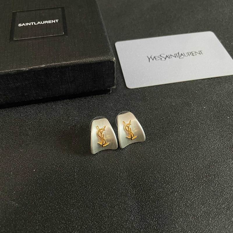 Saint Laurent Cassandre YSL stud earrings in brushed silver with gold monogram logo, displayed with branded box and authenticity card